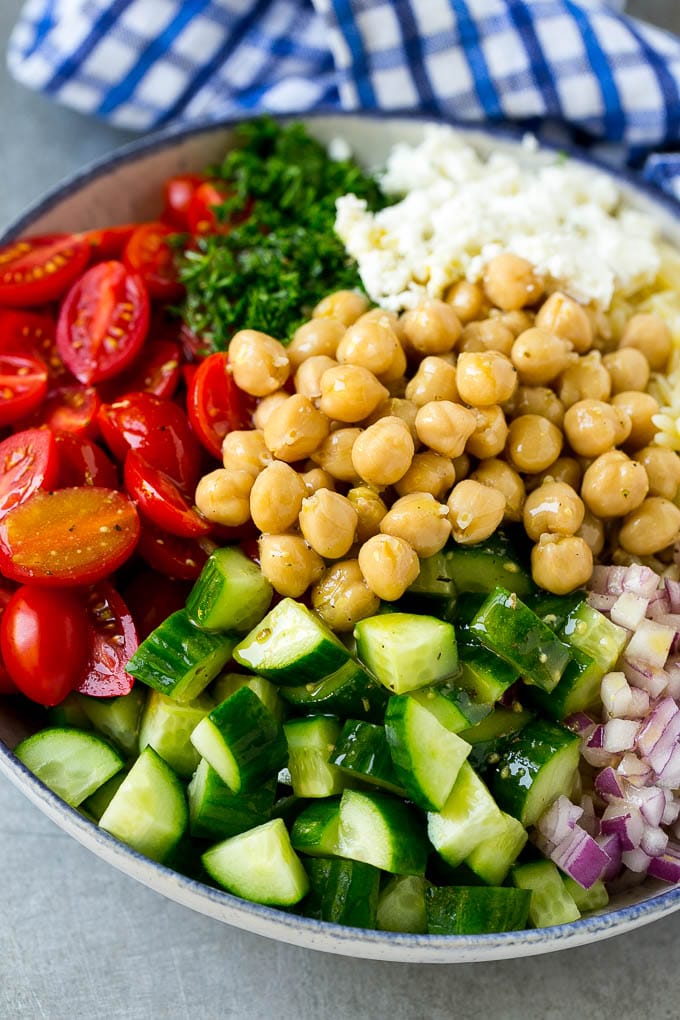 Orzo Salad Recipe | Orzo Pasta Salad | Greek Orzo Salad | Mediterranean Orzo Salad #pastasalad #orzo #greekfood #salad #sraye A bowl of orzo pasta, tomatoes, cucumbers, red onions, chickpeas and feta cheese topped with dressing.