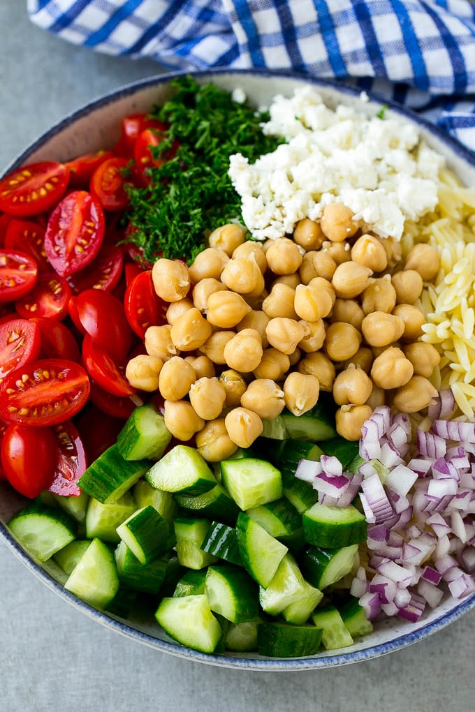 Orzo Salad Recipe | Orzo Pasta Salad | Greek Orzo Salad | Mediterranean Orzo Salad #pastasalad #orzo #greekfood #salad #sraye A bowl of orzo pasta, cucumbers, cherry tomatoes, feta cheese, red onions, herbs and chickpeas.