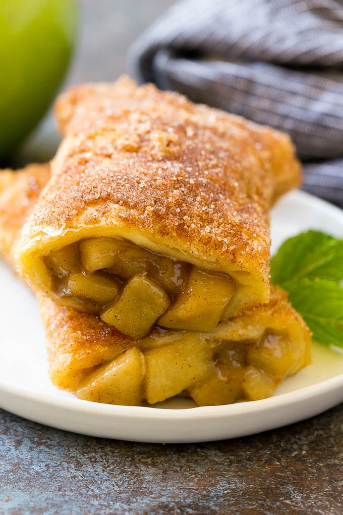 Fried Apple Pies Recipe | McDonald's Copycat Recipe | Apple Pie | Apple Hand Pies #pie #apples #applepie #dessert #snack #sraye A cross section of a fried apple pie on a plate.