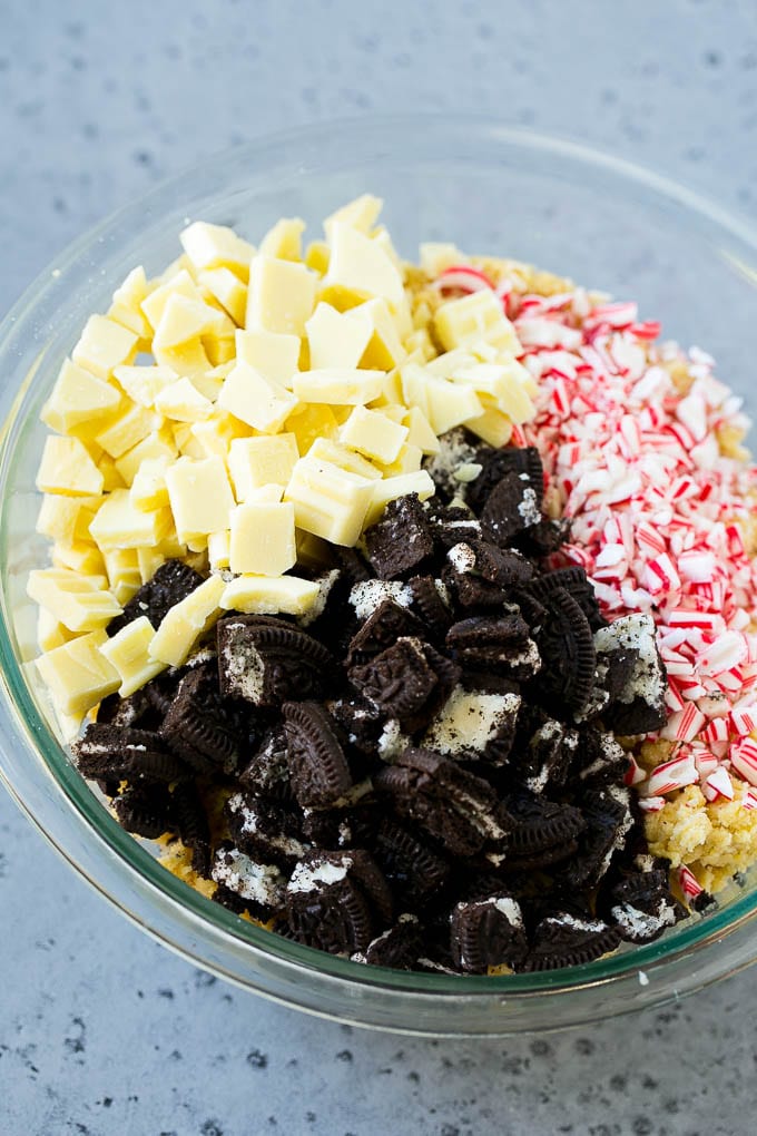 Oreo Peppermint Cookies Recipe | Candy Cane Cookies | Oreo Cookies #oreo #peppermint #cookies #baking #Christmas #sweets #sraye A bowl of dough with Oreo pieces, white chocolate chunks and crushed candy canes.
