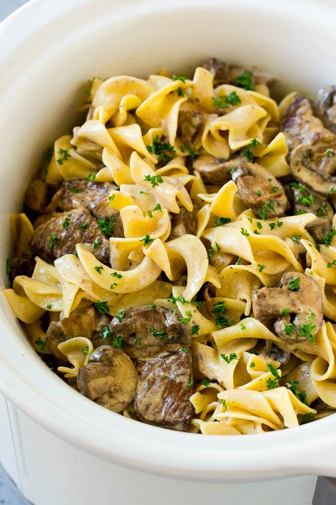 Slow Cooker Beef Stroganoff Recipe | Crock Pot Beef Stroganoff | Beef Recipe #slowcooker #crockpot #beef #mushrooms #pasta #dinner #sraye Slow cooker beef stroganoff with chunks of beef, mushrooms and egg noodles topped with parsley.