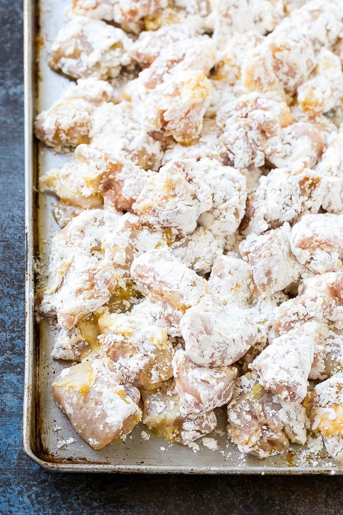 Sweet and Sour Chicken Recipe | Chinese Food Copycat Recipe | Chicken with Pineapple #chicken #chinesefood #pineapple #stirfry #takeout #dinner #sraye Chicken pieces coated in egg and flour on a baking sheet.