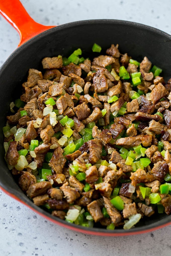 Philly Cheesesteak Dip Recipe | Cheesy Dip | Baked Cheese Dip #steak #dip #appetizer #cheese #sraye Seared rib eye steak, peppers and onions in a pan.