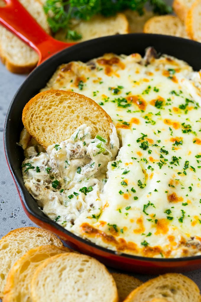 Philly Cheesesteak Dip Recipe | Cheesy Dip | Baked Cheese Dip #steak #dip #appetizer #cheese #sraye Philly cheesesteak dip with a baguette piece scooping some dip out.