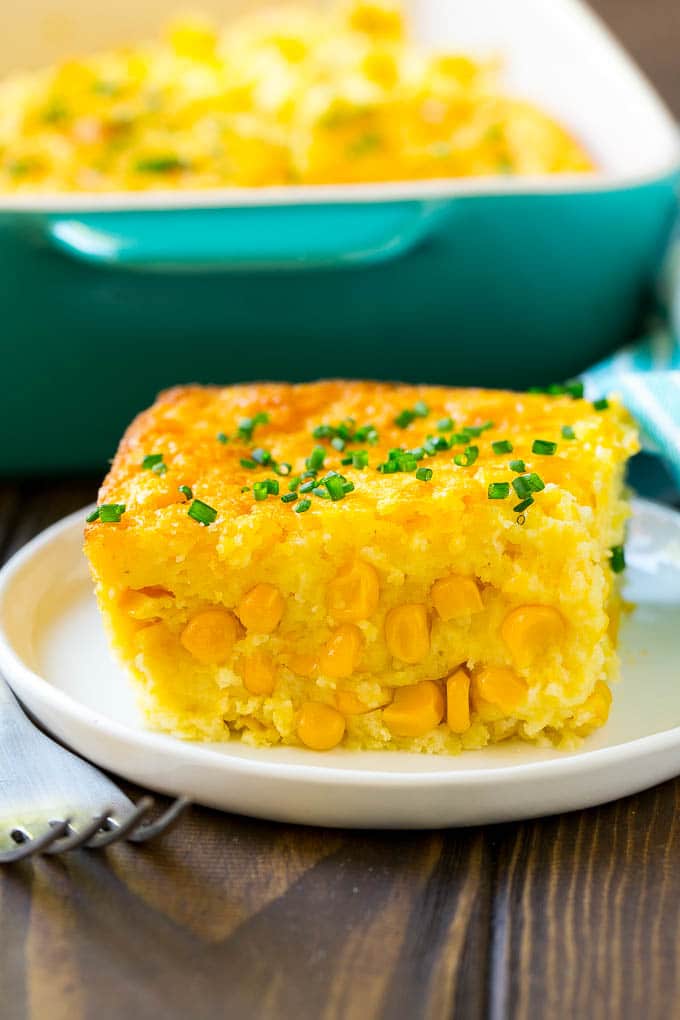 Corn Pudding Recipe | Corn Casserole | Corn Side Dish #corn #pudding #casserole #sidedish #thanksgiving #dinner #sraye A serving of corn pudding on a plate, garnished with chives.