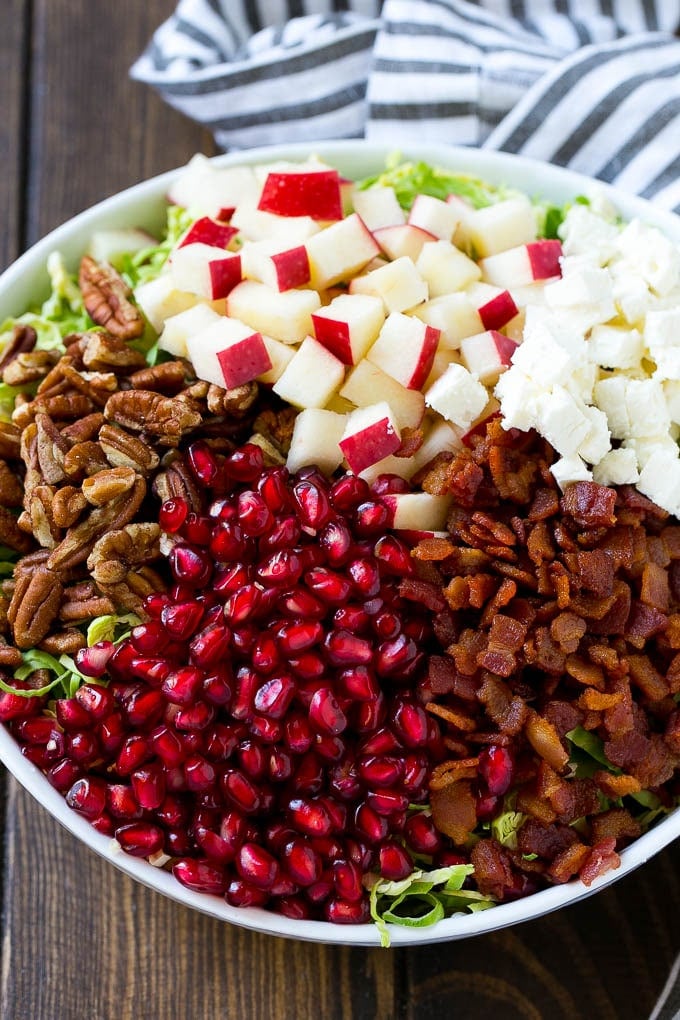 Brussels Sprout Salad Recipe | Shredded Brussels Sprouts Salad | Fall Salad #salad #brusselssprouts #bacon #thanksgiving #pomegranate #apple #dinner #sraye Shredded brussels sprouts topped with pomegranate seeds, bacon, feta cheese and apples.