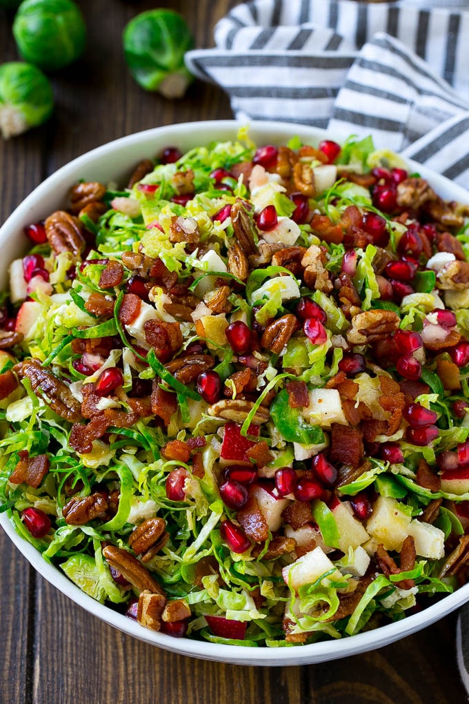 Brussels Sprout Salad Recipe | Shredded Brussels Sprouts Salad | Fall Salad #salad #brusselssprouts #bacon #thanksgiving #pomegranate #apple #dinner #sraye A bowl of salad made with pomegranate, bacon and apples.