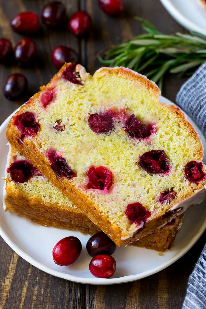 Cranberry Bread Recipe | Cranberry Loaf | Cranberry Orange Bread #cranberry #bread #baking #dessert #fall #sraye A plate with two slices of cranberry bread and fresh cranberries for garnish.