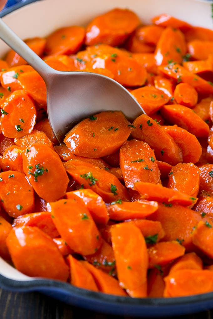 Glazed Carrots Recipe | Brown Sugar Carrots | Carrot Side Dish #carrots #brownsugar #sidedish #glutenfree #thanksgiving #fall #dinner #sraye Glazed carrots in a skillet with a serving spoon.