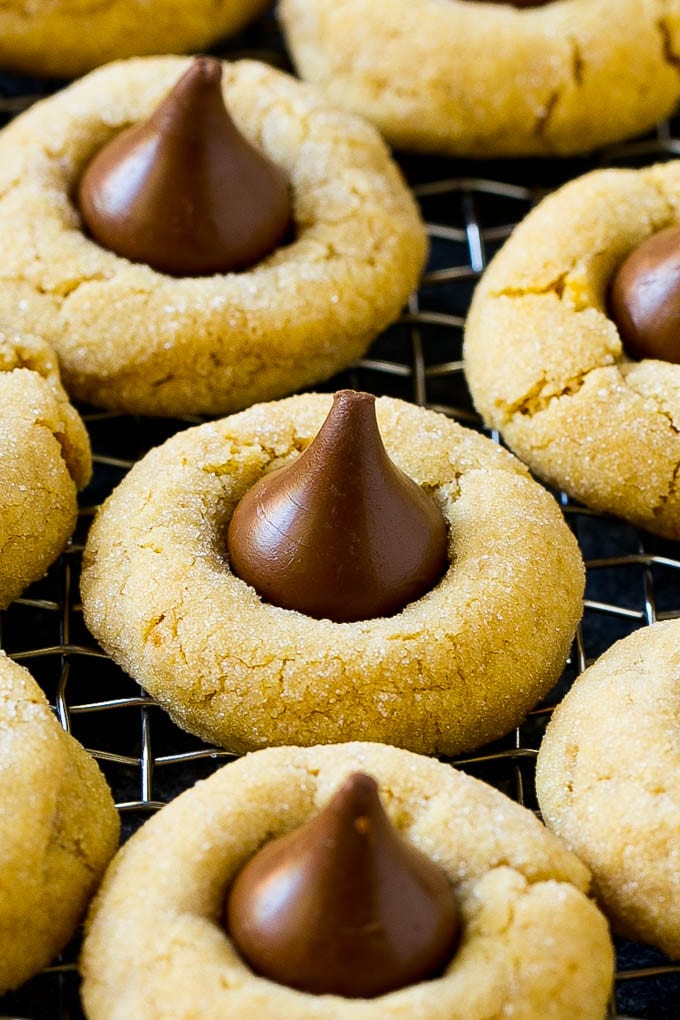 Peanut Butter Blossoms Recipe | Hershey Kiss Cookies | Chocolate Peanut Butter Cookies #cookies #peanutbutter #chocolate #dessert #baking #christmas #christmascookies #sraye Peanut butter blossom cookies on a cooling rack.