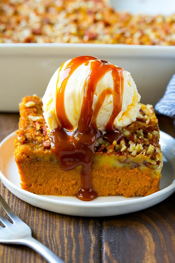 Pumpkin Dump Cake Recipe | Pumpkin Cake | Pumpkin Pie Cake #pumpkin #cake #pecans #fall #thanksgiving #dessert #sraye A slice of pumpkin dump cake topped with ice cream and caramel sauce.