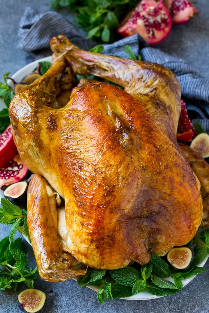 Roast Turkey Recipe | Thanksgiving Turkey | Holiday Turkey | Baked Turkey #turkey #thanksgiving #christmas #dinner #glutenfree #sraye A Thanksgiving roast turkey on a serving platter garnished with herbs, pomegranate and figs.