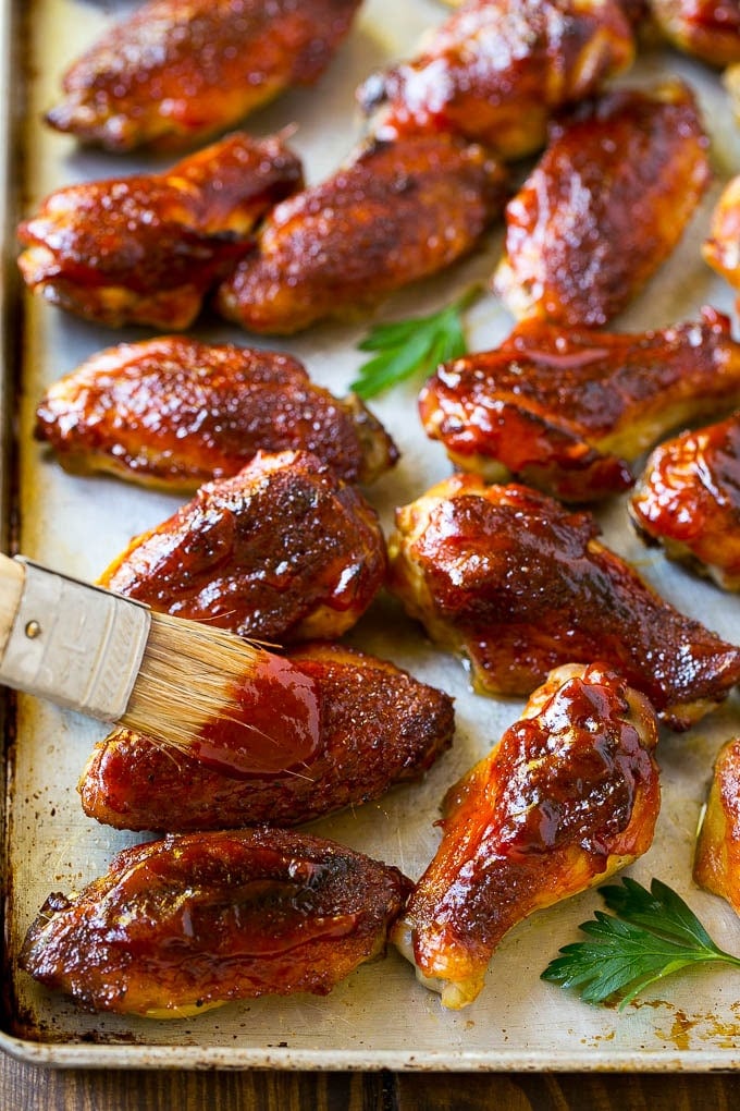 Smoked Chicken Wings | Barbecue Chicken Wings | BBQ Chicken Wings #chicken #wings #bbq #barbecue #appetizer #dinner #sraye BBQ sauce brushed onto a sheet pan of smoked chicken wings.