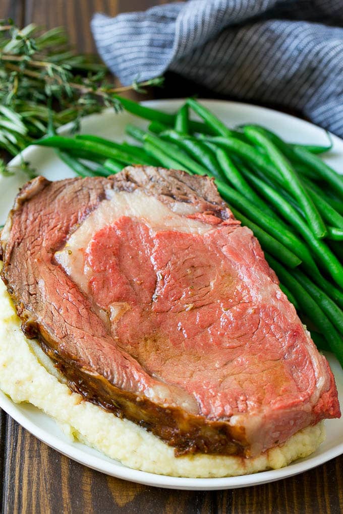 Smoked Prime Rib Recipe | Easy Prime Rib | Smoked Beef | Holiday Prime Rib #primerib #beef #smoker #dinner #sraye #christmas #thanksgiving #lowcarb #keto A slice of prime rib over mashed potatoes with green beans on the side.