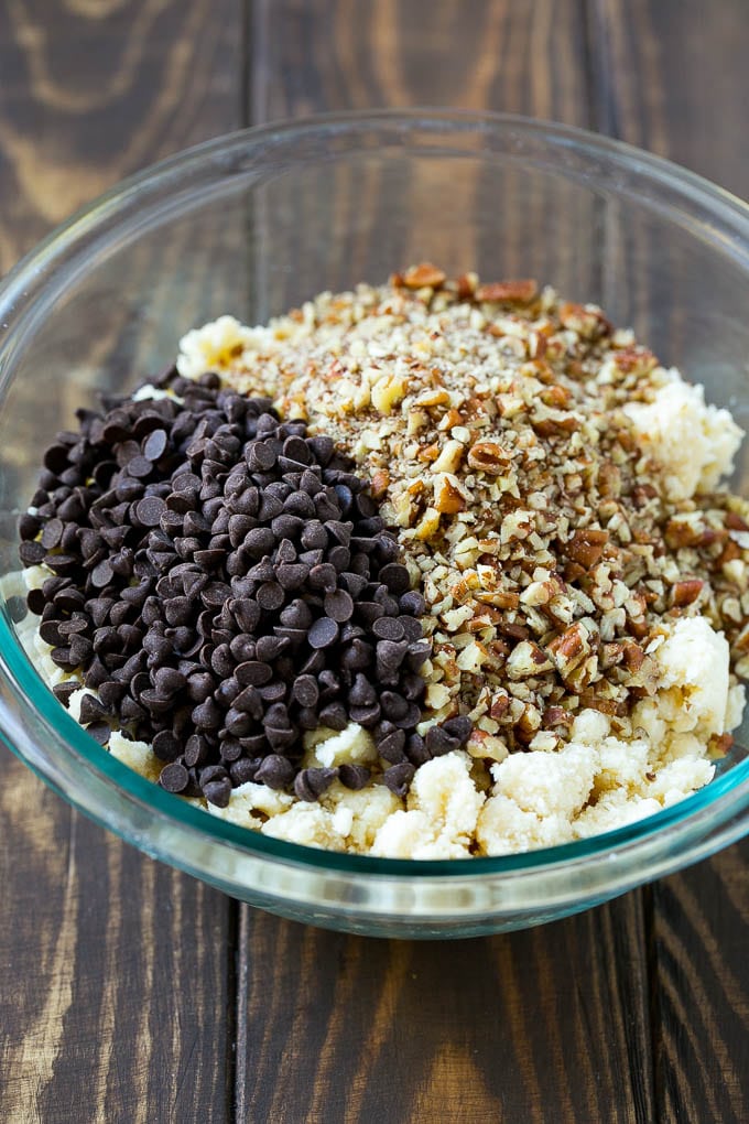 Snowball Cookies Recipe | Mexican Wedding Cookies | Russian Tea Cakes #cookies #pecan #chocolate #baking #dessert #christmas #sraye A bowl of dough topped with miniature chocolate chips and chopped pecans.