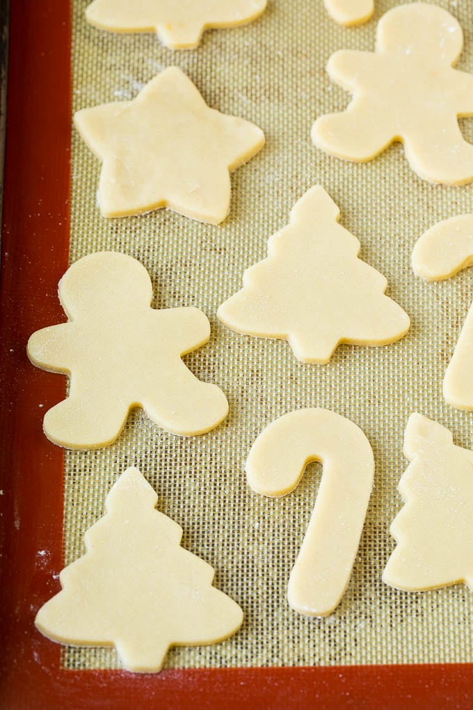 Christmas Sugar Cookies Recipe | Christmas Cookies #cookies #frosting #sprinkles #sugarcookies #christmas #dessert #sraye Cookie dough cut into holiday shapes on a baking sheet.