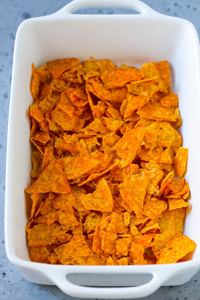 Crushed nacho chips in the bottom of a casserole dish.