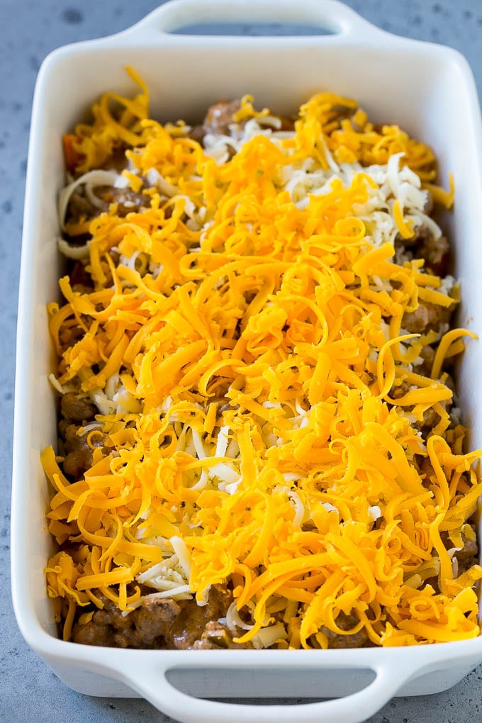 A dish layered with chips, ground beef and shredded cheese.