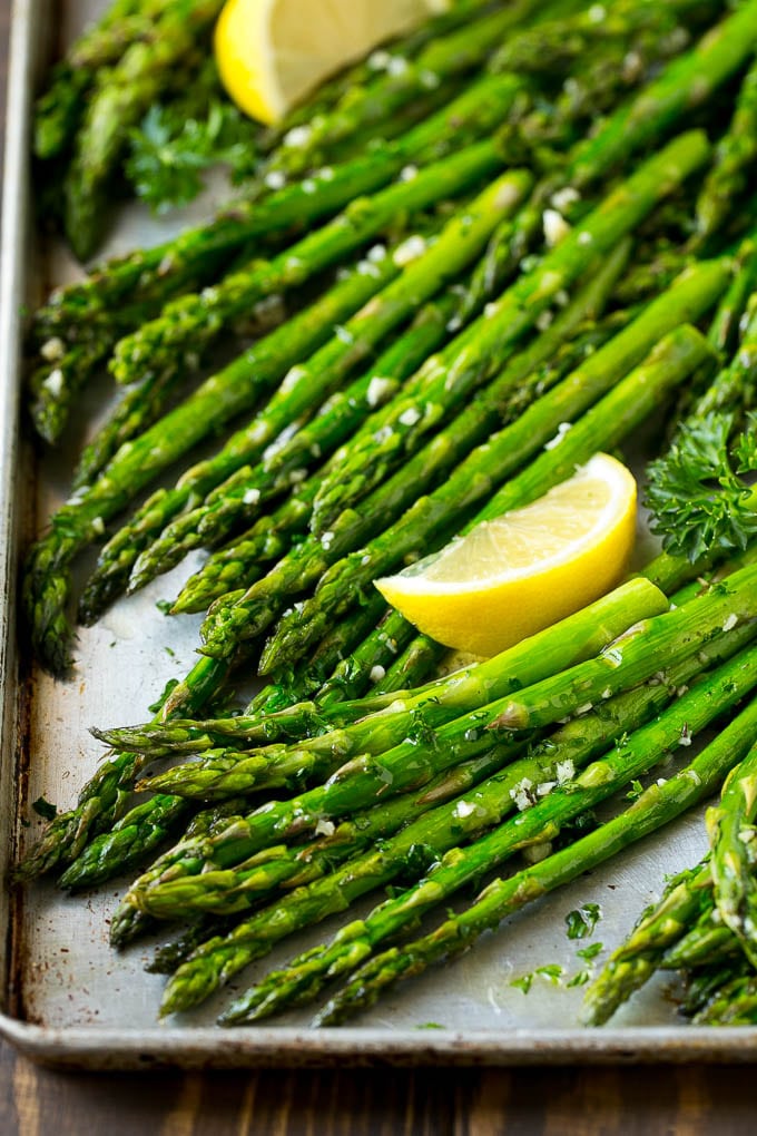 Roasted Asparagus Recipe | Baked Asparagus | Asparagus Side Dish #asparagus #garlic #sidedish #keto #lowcarb #dinner #sraye Roasted asparagus on a sheet pan, topped with chopped parsley and garnished with lemon wedges.