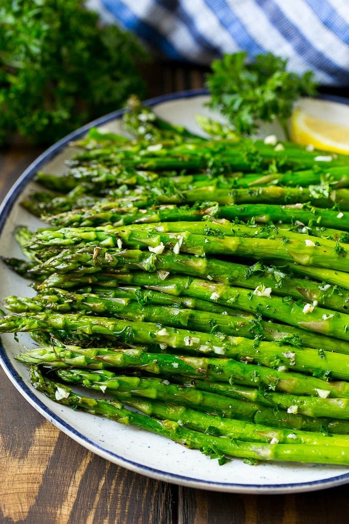 Roasted Asparagus Recipe | Baked Asparagus | Asparagus Side Dish #asparagus #garlic #sidedish #keto #lowcarb #dinner #sraye A serving plate of roasted asparagus topped with chopped parsley.
