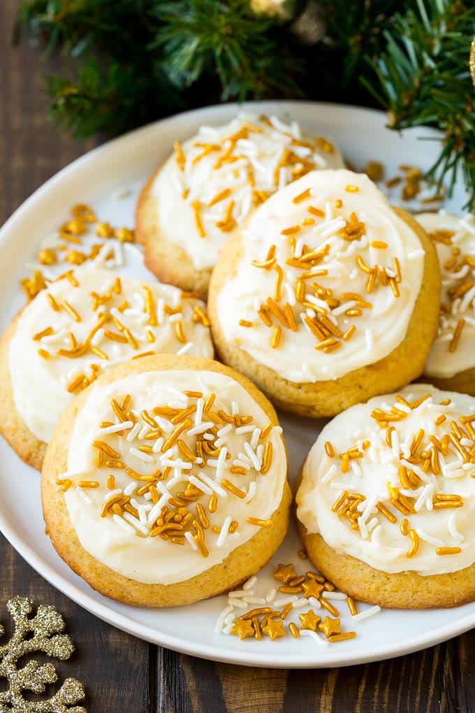 Eggnog Cookies Recipe | Holiday Cookies | Christmas Cookies #cookies #eggnog #baking #christmas #sprinkles #dessert #sraye Eggnog cookies topped with frosting and gold sprinkles on a serving plate.