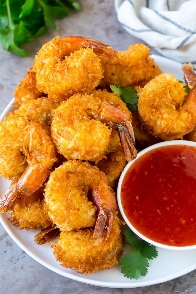 Coconut Shrimp Recipe | Fried Shrimp | Shrimp Appetizer #shrimp #coconut #appetizer #seafood #dinner #sraye A plate of coconut shrimp with a bowl of sweet chili sauce.