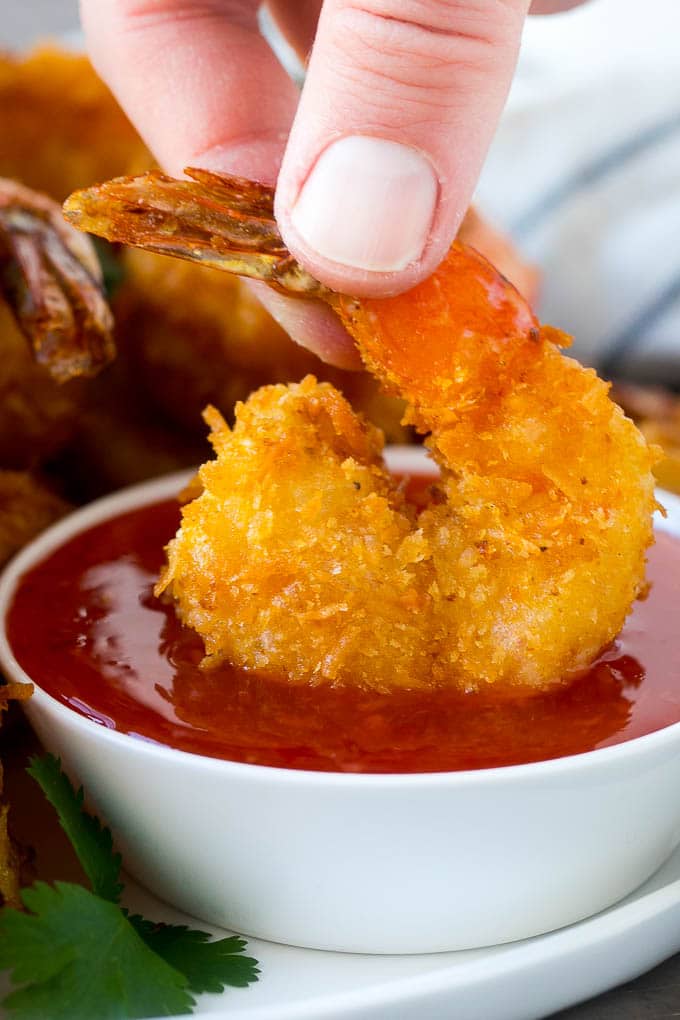 Coconut Shrimp Recipe | Fried Shrimp | Shrimp Appetizer #shrimp #coconut #appetizer #seafood #dinner #sraye A hand dipping a crispy prawn into a bowl of sweet chili sauce.