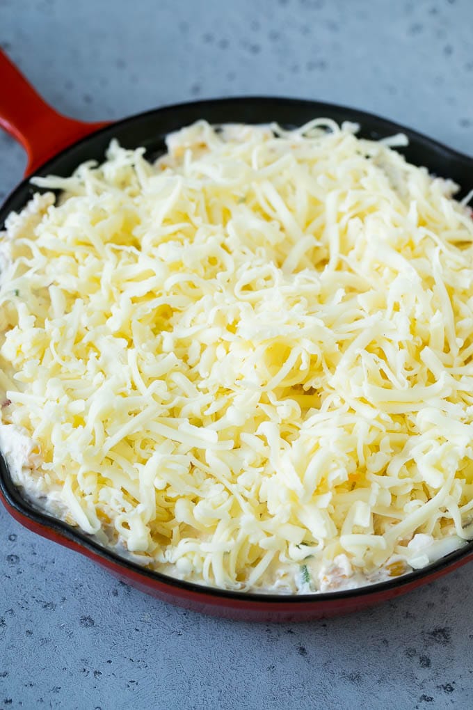 Corn Dip Recipe | Hot Cheese Dip | Bacon Dip #corn #dip #bacon #cheese #appetizer #snack #sraye A skillet of corn dip covered with shredded cheese.