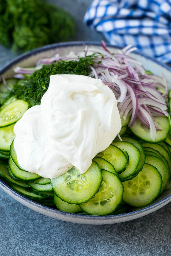 Creamy Cucumber Salad Recipe | German Cucumber Salad | Cucumber Salad #cucumber #salad #dinner #lunch #sraye #cucumbersalad Cucumbers, red onion and dill in a bowl topped with creamy dressing.