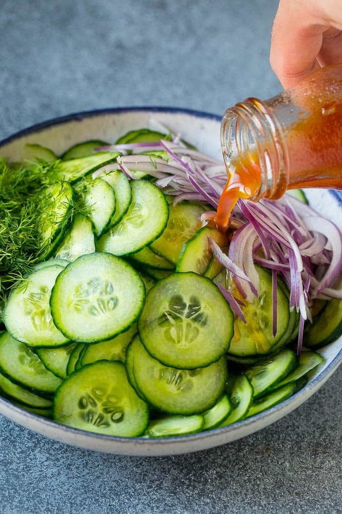 Cucumber Salad Recipe | Cucumber Dill Salad | Cucumber Recipe #cucumbers #salad #glutenfree #sidedish #sraye Dressing being poured over sliced vegetables and fresh dill.