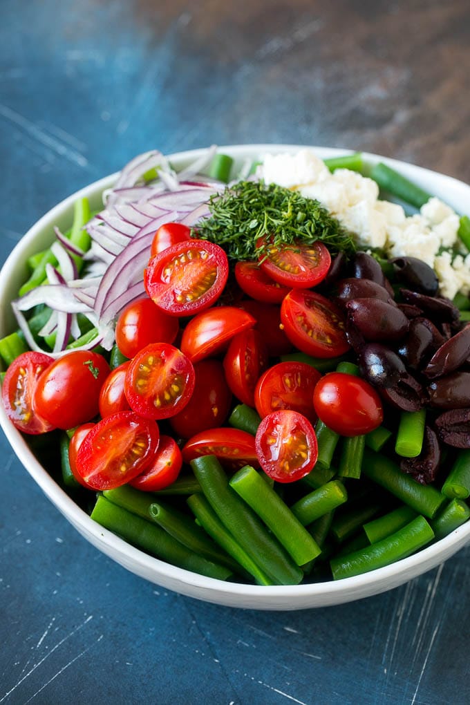 Green Bean Salad Recipe | String Bean Salad | Chopped Salad #greenbeans #tomatoes #olives #salad #cleaneating #lowcarb #glutenfree #sraye Vegetables like cherry tomatoes, red onion and olives in a bowl with feta cheese.