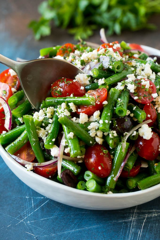 Green Bean Salad Recipe | String Bean Salad | Chopped Salad #greenbeans #tomatoes #olives #salad #cleaneating #lowcarb #glutenfree #sraye A serving spoon in a bowl of green bean salad.