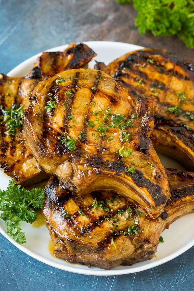 Pork Chop Marinade Recipe | Marinated Pork Chops | Grilled Pork Chops #pork #porkchops #grilling #dinner #sraye Pork chop marinade on grilled pork chops. The pork chops are on a serving plate garnished with parsley.