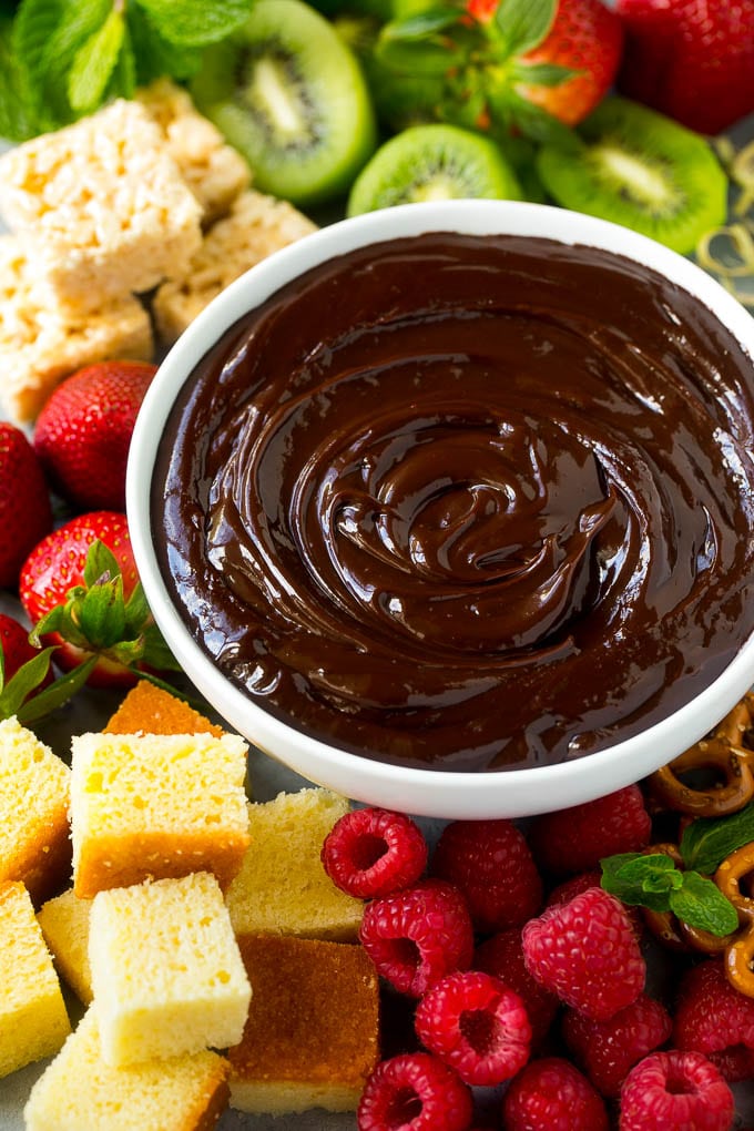 Chocolate Fondue Recipe | Chocolate Sauce | Chocolate Dip #chocolate #dessert #glutenfree #fondue #sraye A bowl of chocolate fondue surrounded by fruit, cake, rice krispy treats and pretzels.