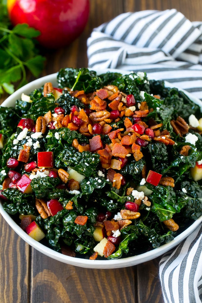 Apple Kale Salad Recipe | Kale Recipe | Fall Salad #kale #apples #bacon #salad #feta #dinner #lunch #sraye A bowl of tuscan kale salad garnished with cooked bacon.