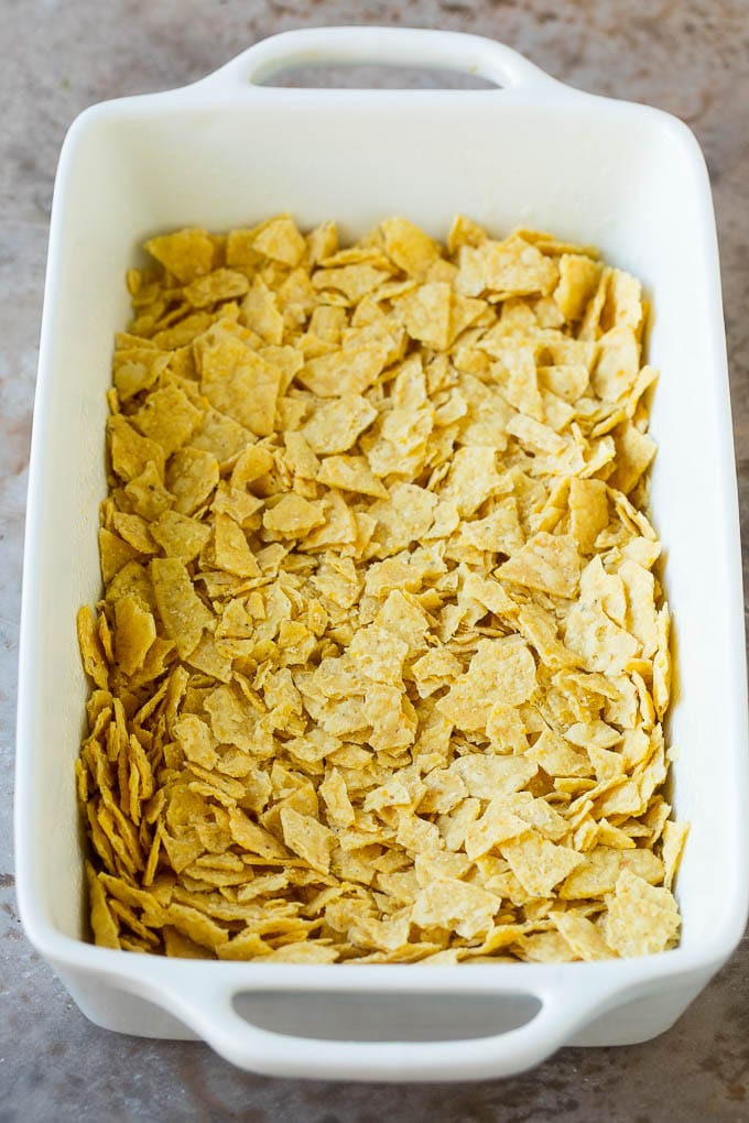 Taco Casserole Recipe | Mexican Casserole | Beef Casserole #casserole #tacos #beef #dinner #cheese #sraye Crushed tortilla chips in a casserole dish.