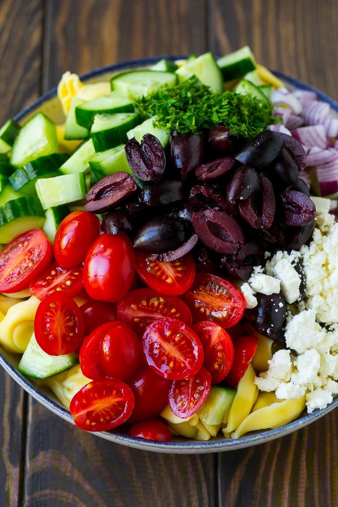 Greek Tortellini Salad Recipe | Pasta Salad | Tortellini Salad | Greek Salad #greek #tortellini #pasta #salad #cucumbers #olives #dinner #sraye Tortellini in a bowl topped with olives, tomatoes, cucumber and feta cheese.