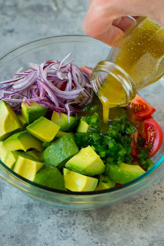 Tomato Avocado Salad Recipe | Avocado Salad | Tomato Salad #salad #tomato #avocado #glutenfree #cleaneating #dinner #sraye #healthy Dressing being poured over chopped veggies.