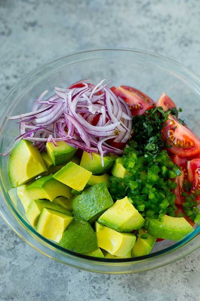 Tomato Avocado Salad Recipe | Avocado Salad | Tomato Salad #salad #tomato #avocado #glutenfree #cleaneating #dinner #sraye #healthy Pieces of avocado, tomato, red onion and minced jalapeno in a salad bowl.
