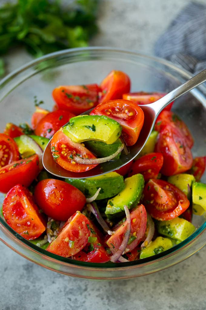 Tomato Avocado Salad Recipe | Avocado Salad | Tomato Salad #salad #tomato #avocado #glutenfree #cleaneating #dinner #sraye #healthy A serving spoon of veggies in a lime dressing.