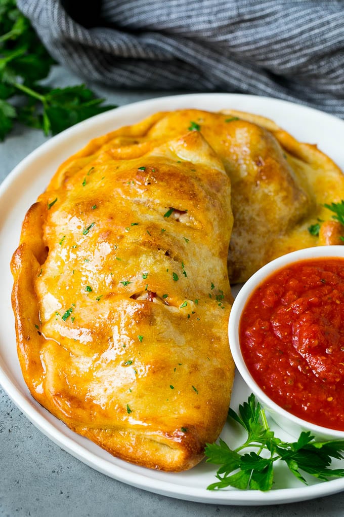 Calzone Recipe | Pizza Pockets #pizza #calzone #pepperoni #sausage #peppers #dinner #sraye #cheese A homemade calzone served with pizza sauce.