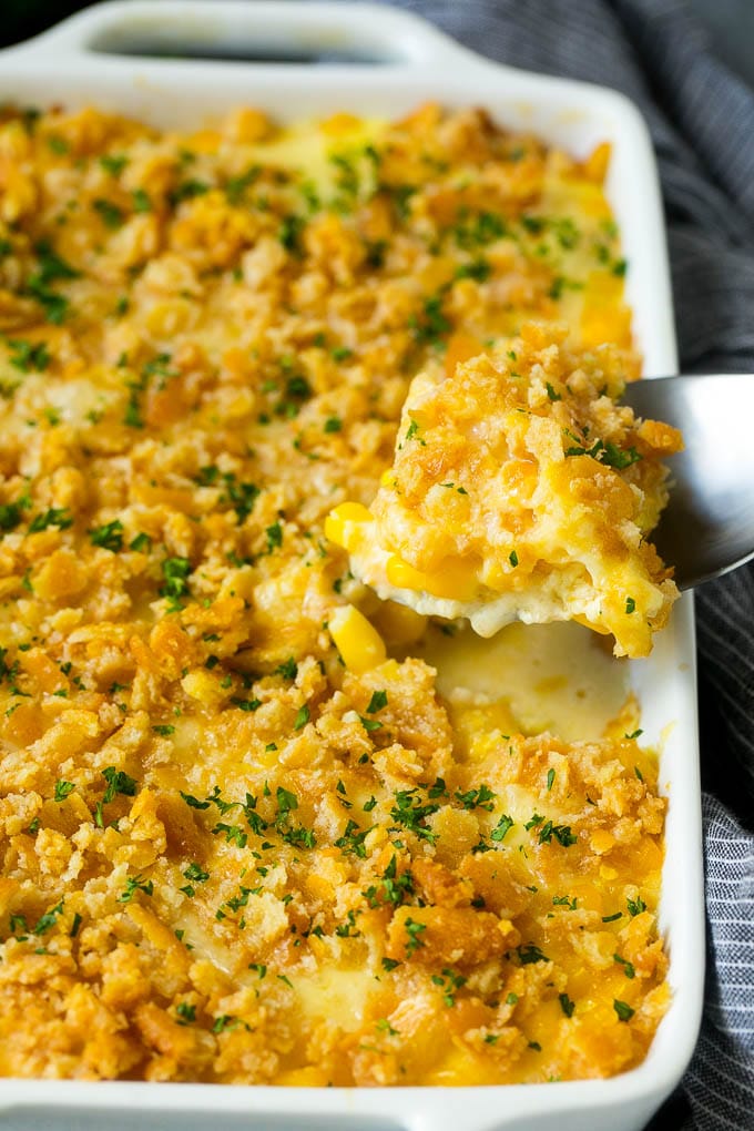 Scalloped Corn | Corn Casserole #corn #casserole #cheese #sidedish #dinner #sraye A serving spoon lifting out a portion of scalloped corn.