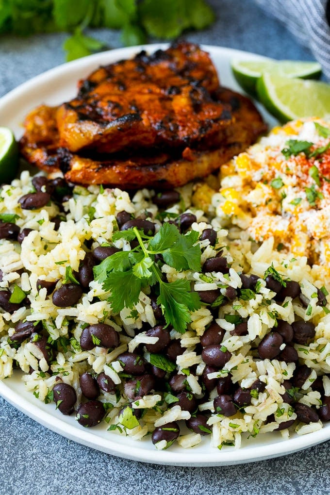 Black Beans and Rice Recipe | Cuban Black Beans | Beans and Rice #beans #rice #blackbeans #sidedish #glutenfree #dinner #sraye A plate of black beans and rice with grilled pork and Mexican corn.