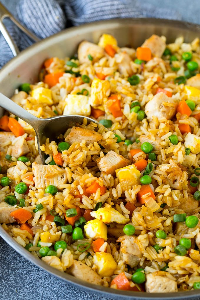 Chicken Fried Rice Recipe | Chinese Fried Rice #rice #chicken #peas #carrots #sidedish #dinner #sraye A serving spoon in a pan of chicken fried rice.