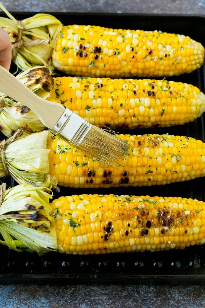 Grilled Corn on the Cob Recipe | Corn Recipe #corn #grilling #summer #sidedish #dinner #sraye Cobs being brushed with herb butter.