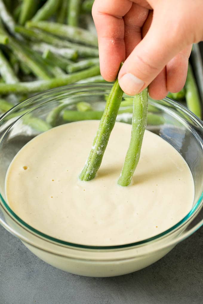 Fried Green Beans Recipe | Green Beans #greenbeans #appetizer #snack #sraye A hand dipping beans into beer batter.