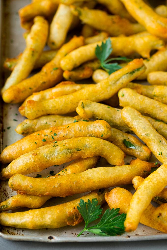 Fried Green Beans Recipe | Green Beans #greenbeans #appetizer #snack #sraye A sheet pan of fried green beans garnished with chopped parsley.