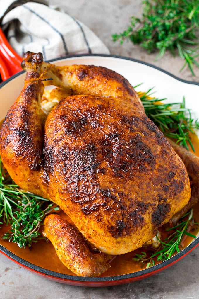 Rotisserie Chicken Recipe | Roasted Chicken #chicken #dinner #sraye #comfortfood A rotisserie chicken in a red skillet with sprigs of fresh herbs.