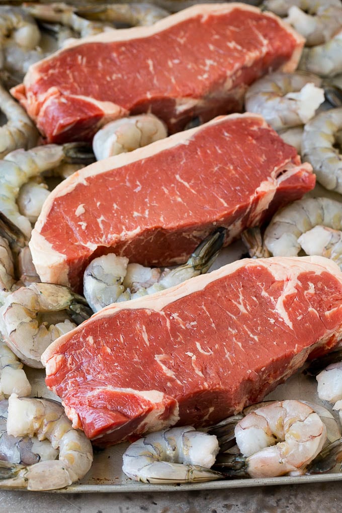Surf and Turf Recipe | Seared Steak #steak #shrimp #keto #lowcarb #dinner #sraye Raw steaks and shrimp on a sheet pan.