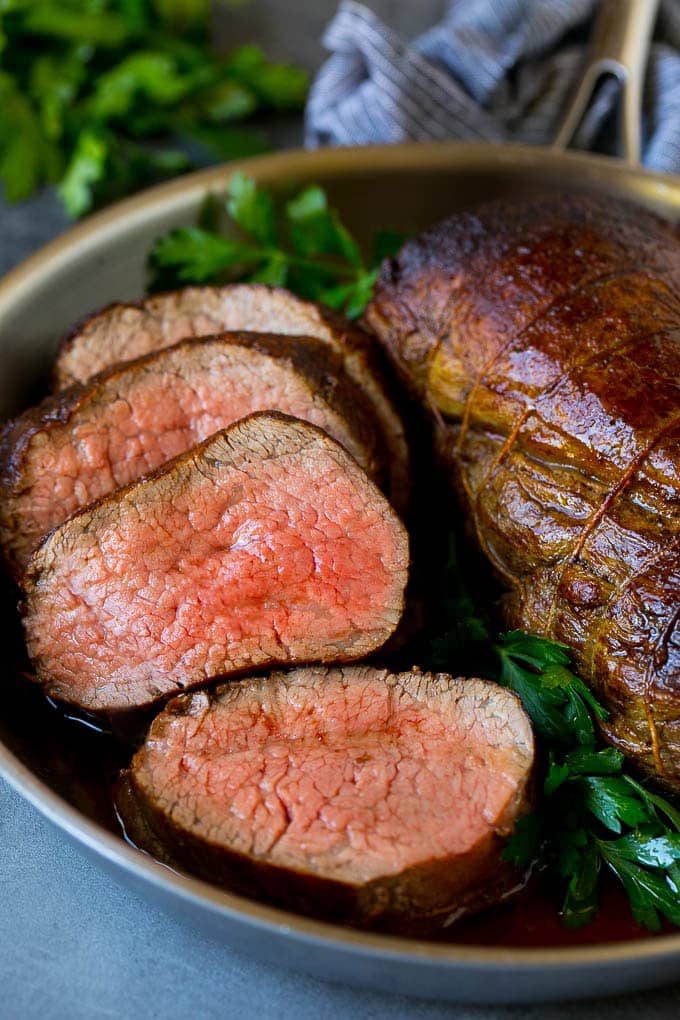 Beef Tenderloin with Garlic Butter #beef #steak #dinner #sraye A sliced beef tenderloin recipe in a pan, garnished with fresh parsley.